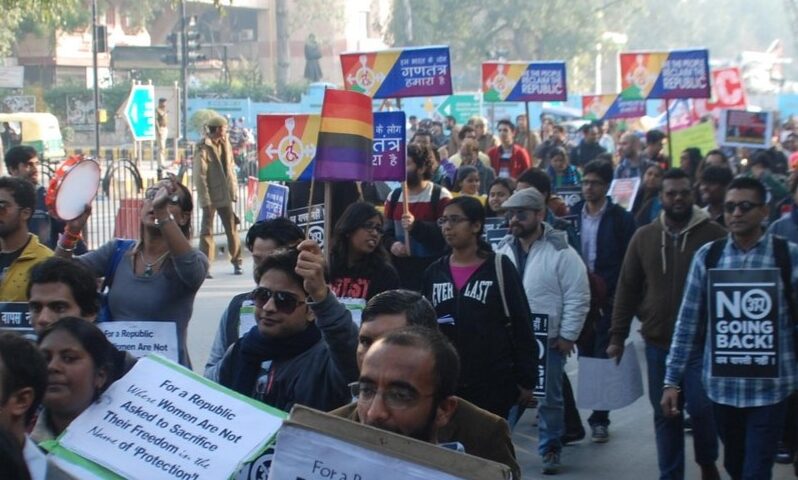 Crowd of people carrying rainbow signs at a protest in India