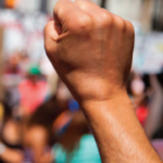 Image of a fist in the air at a protest against a blurred backrgoundblure