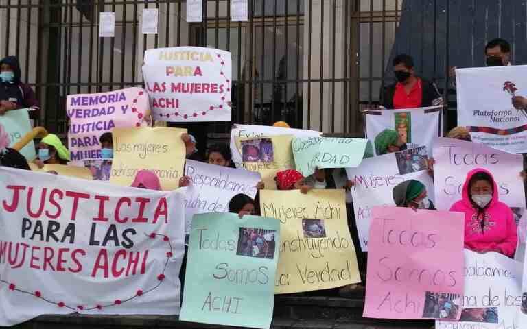 Indigenous women outside of Guatemala's highest court holding handmade signs