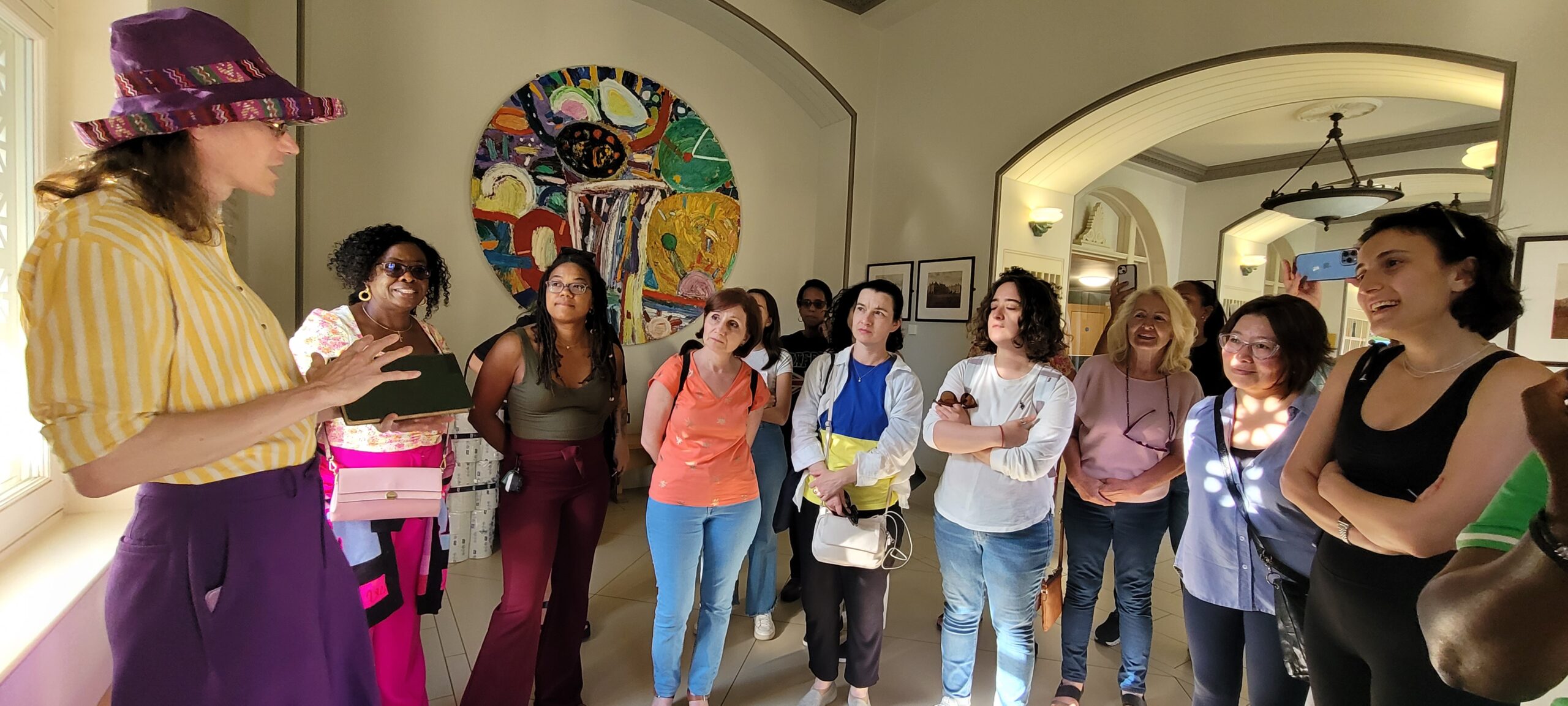 group of women gathered listening to an individual speak with various pieces of artwork in the background