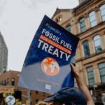 person holding poster that states "It's time for a Fossil Fuel Non-Proliferation Treaty"