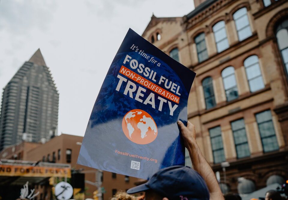 person holding poster that states "It's time for a Fossil Fuel Non-Proliferation Treaty"