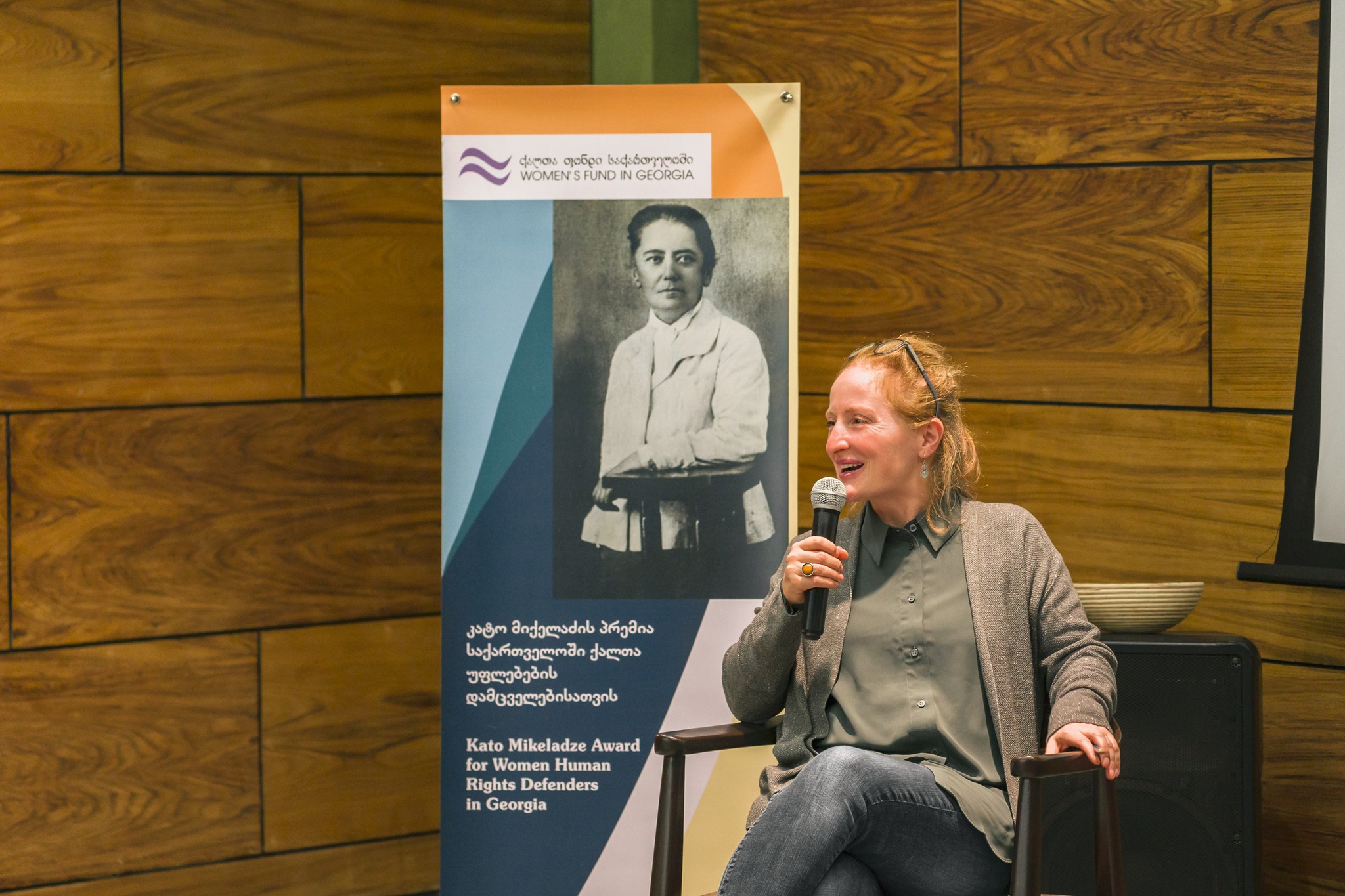 women sitting with a microphone in front of a poster that states "Women's Fund in Georgia".